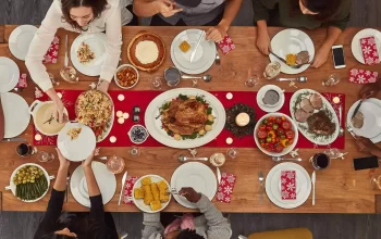 A group of people sitting at a table with turkey in the center and lots of food in a plate