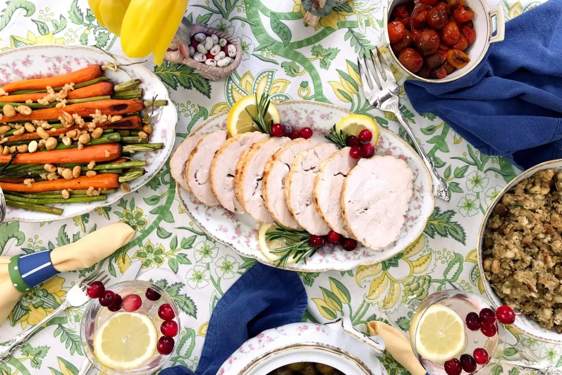 Sliced turkey roast placed on a table which is decorated with different food delicacies.