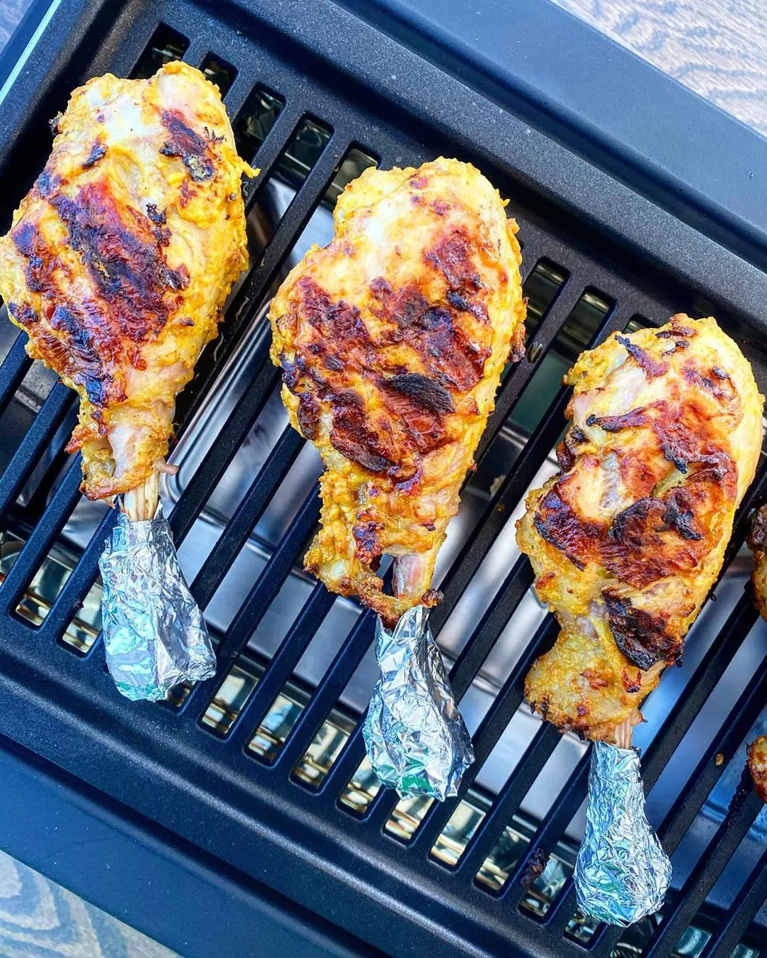 Grilled turkey drumsticks placed on griller.