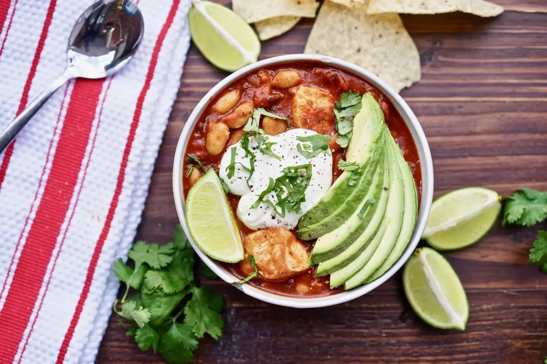 Turkey chili topped with avocado, yogurt and lemon served in a bowl.