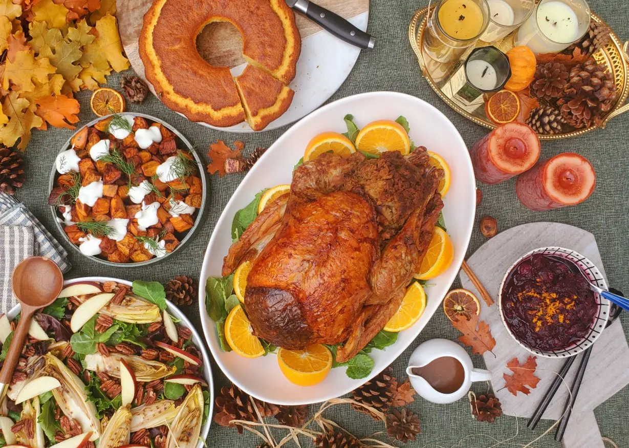 A Thanksgiving feast spread out on a table, featuring a roasted turkey, assorted vegetables, and other delicious foods.