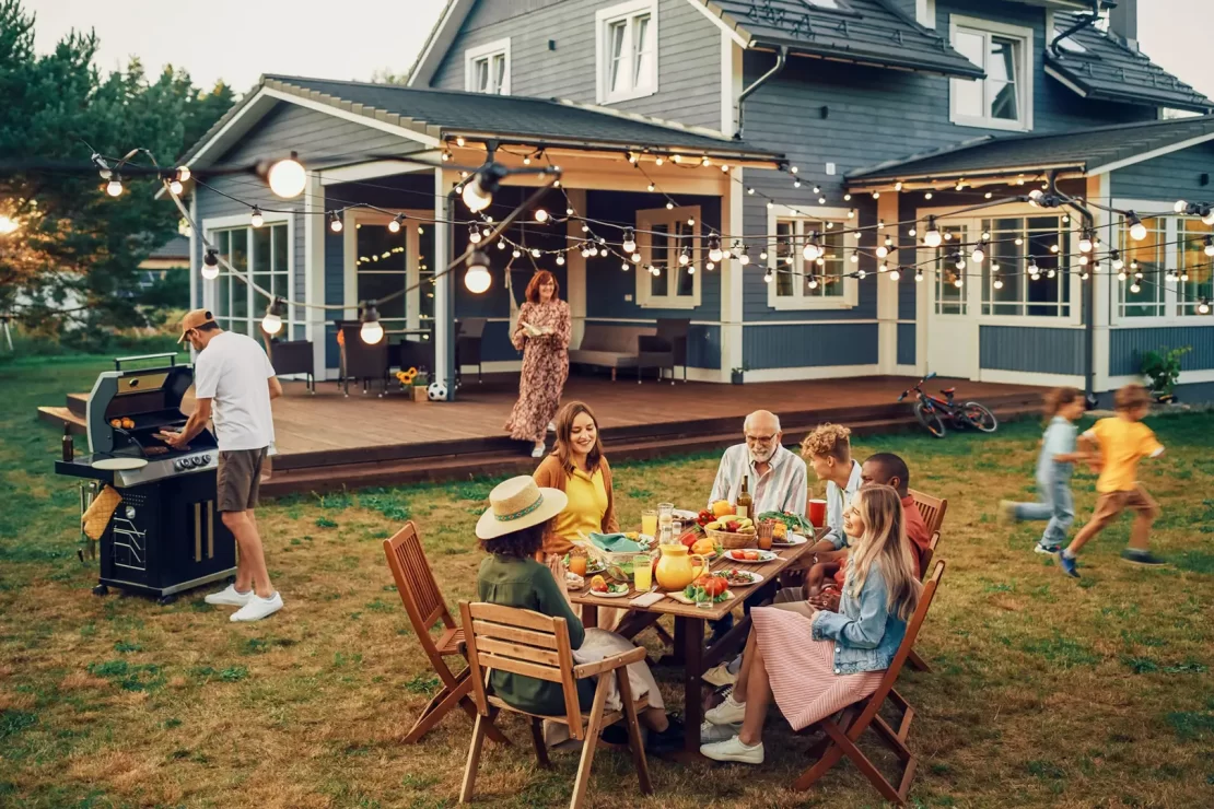 A family happily dining outdoors on the patio under string lights.
