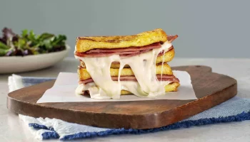 Monte Cristo sandwich with turkey bacon placed on a wooden tray