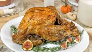 Cooked turkey with herbs and vegetables on a dining table.
