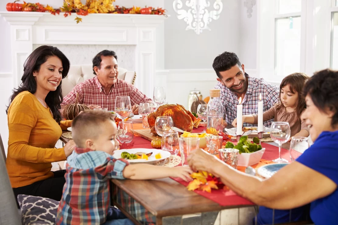 A family gathered around a table, celebrating Thanksgiving with a delicious meal and warm smiles.