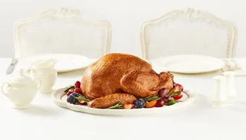 Roasted whole turkey garnished with fruits placed on a table.